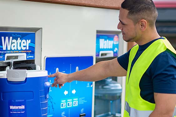 Customer refilling their water cooler at a Watermill Express station